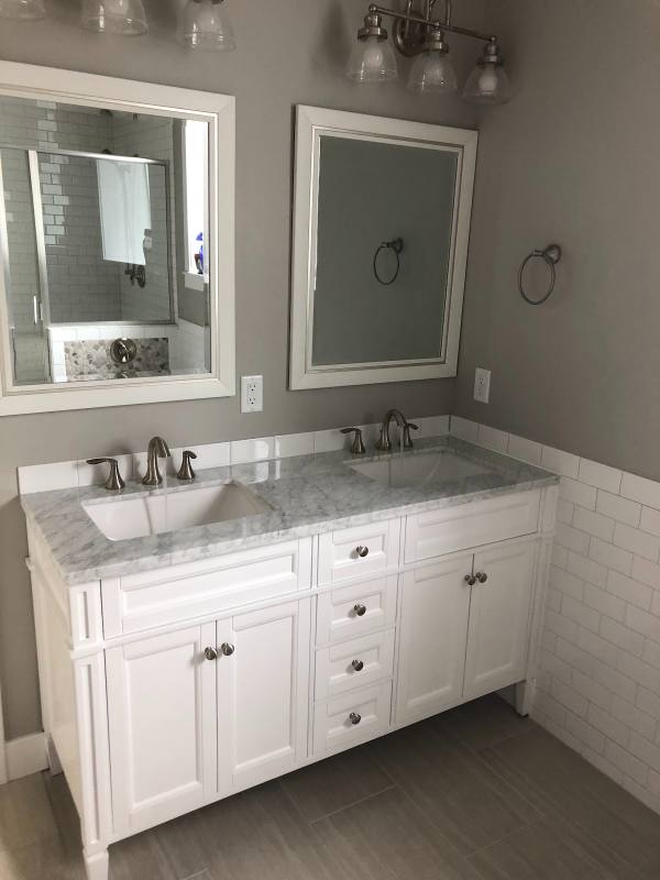 White double vanity with marble top and two brushed-nickel faucets