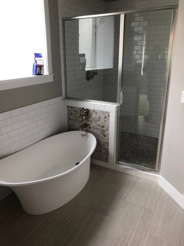 Freestanding tub with wall-mounted tub filler next to a tiled shower